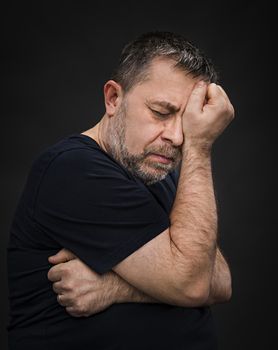 Headache. Portrait of an elderly man with face closed by hand