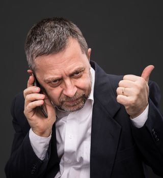 Handsome middle-aged business man speaks on a mobile phone and gesturing