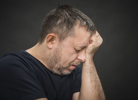 Headache. Portrait of an elderly man with face closed by hand