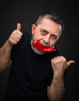 Portrait of elderly man with red pepper in his mouth