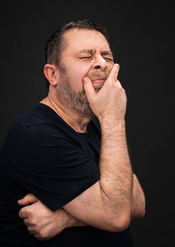 Headache. Portrait of an elderly man with face closed by hand