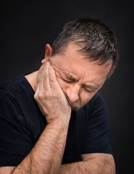 Toothache. Portrait of an elderly man with face closed by hand