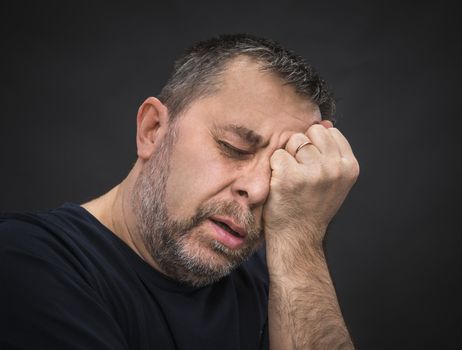 Headache. Portrait of an elderly man with face closed by hand