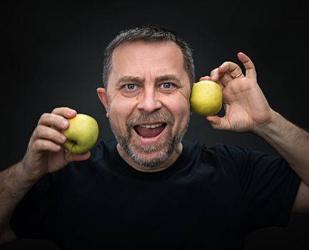 Portrait of emotional middle-aged man with a green apples