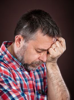 Elderly man suffering from a headache on dark background