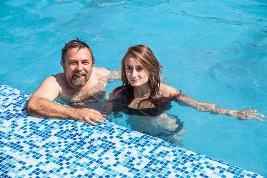 Happy family. Father and daughter swimming in the pool on a sunny day.