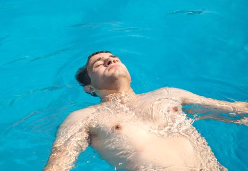 Healthy lifestyle. The young man is swimming in a pool on a sunny day