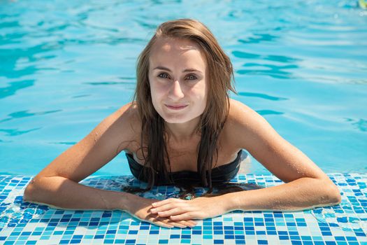 Young beautiful woman sunbathing in the swimming pool