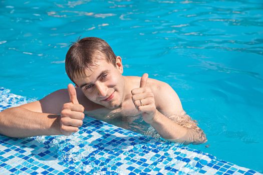 Healthy lifestyle. The young man is swimming in a pool on a sunny day