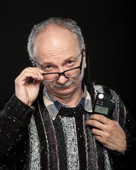 Portrait of a senior photographer with a flash meter and glasses