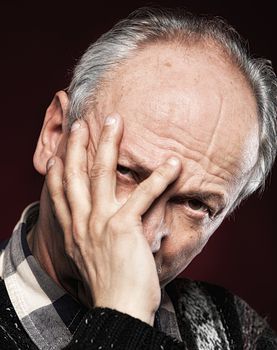 Portrait of an elderly man with face closed by hand 
