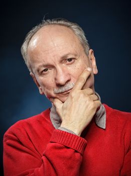 Portrait of an thoughtful  elderly man on a dark blue background