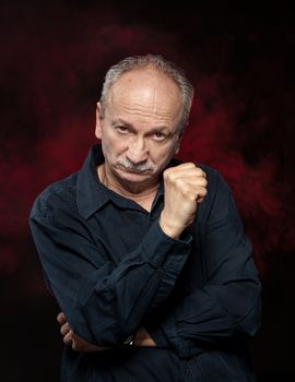 Handsome senior man in black shirt on dark background