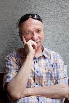 Portrait of an thoughtful elderly man with sunglasses on his forehead