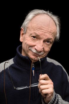 An elderly man with glasses smiling on a dark background