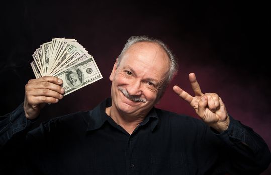 Lucky old man holding with pleasure group of dollar bills