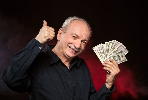 Lucky old man holding group of dollar bills and show OK sign