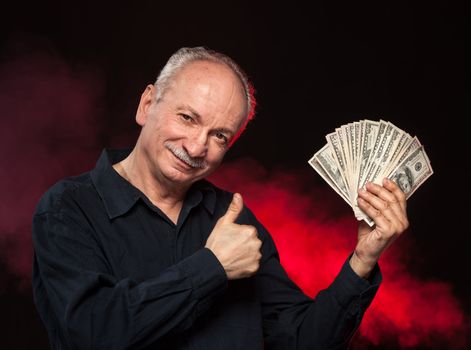 Lucky old man holding with pleasure group of dollar bills