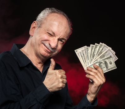 Lucky old man holding with pleasure group of dollar bills