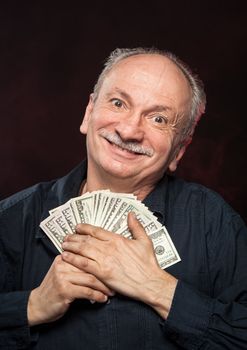 Lucky old man holding with pleasure group of dollar bills