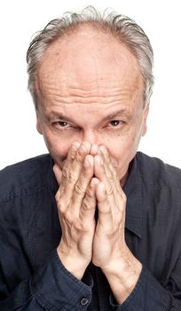 Elderly man covers his face with hand