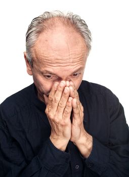 Elderly man covers his face with hand