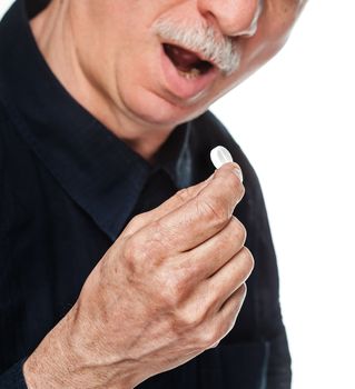 Old man wants to take a pill. Focus on hand