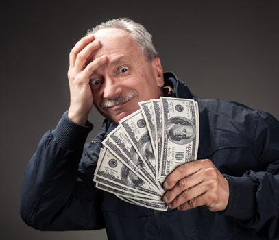 Lucky old man holding with pleasure group of dollar bills. Focus on money