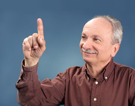 handsome old man pointing up on blue background