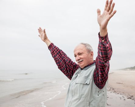 peaceful carefree older man with outstretched arms the coast at foggy day