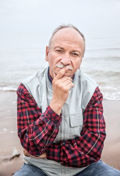 Thoughtful elderly man on the beach on a foggy day