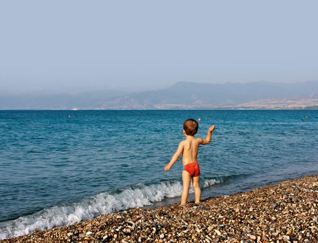 Boy playing with stones on sea beach