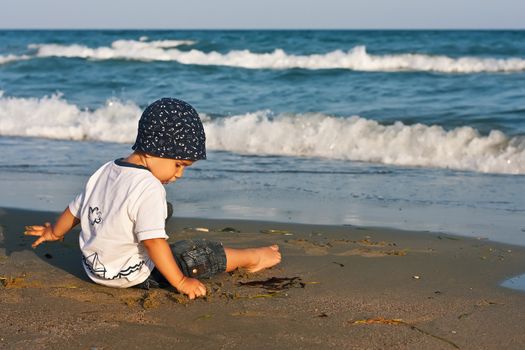 Boy playing with sand sitting on the beach