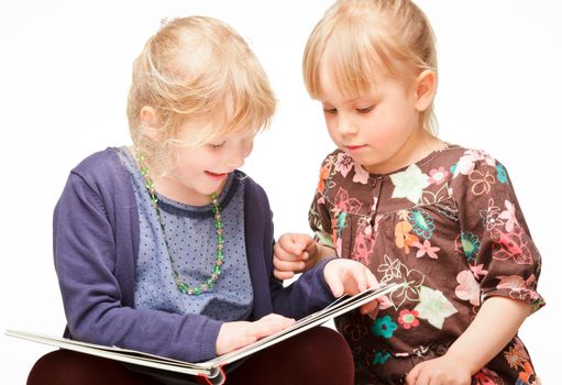 Two cute little girls reading a book