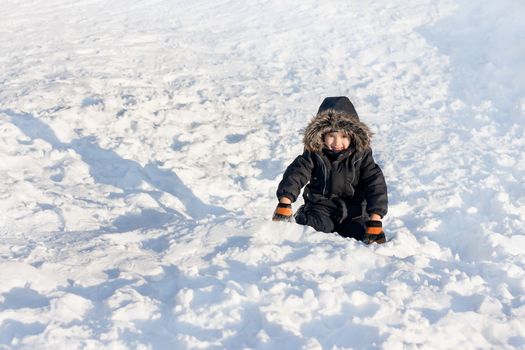 Young boy with tense emotions on face sitting on the snow