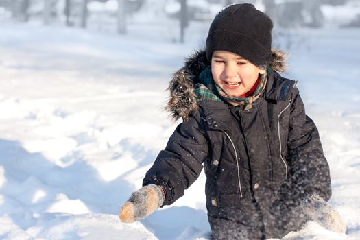 Winter portrait of laughing happy boy full of joy playing in snow