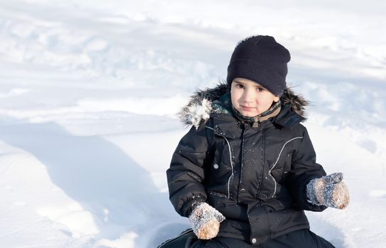 Winter portrait of happy boy full of joy playing in snow