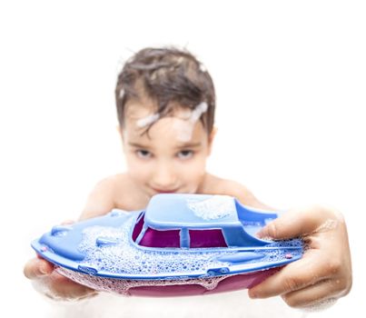 A little boy playing in the bath with a toy boat. Focus on the boat