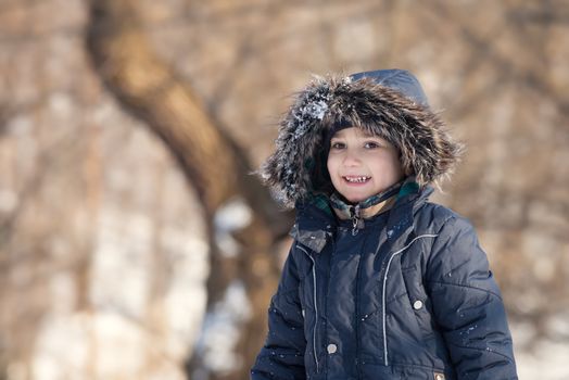 Cute boy walk in the winter park in sunny day