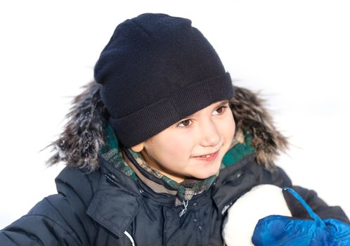 Cute boy in a winter jacket, playing with snow