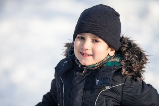 Portrait of cute boy in the winter park in sunny day