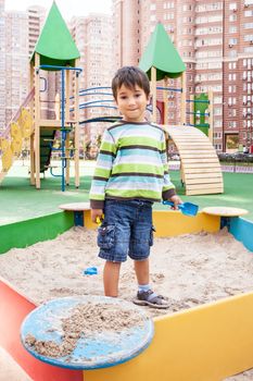 Cute boy playing in sandbox with a sand toys