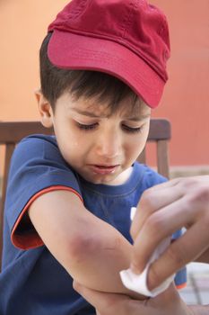 Small boy crying in pain injuring his hand. Father provides first aid