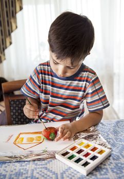 
Home and family. Little boy draws house and easter egg with watercolor