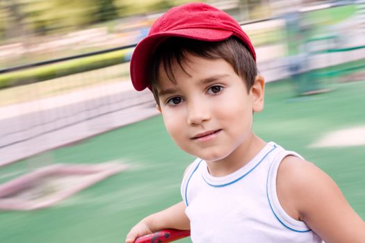 Portrait of a 3-4 years boy playing on the playground with motion blurred background