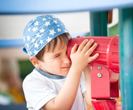 Little boy playing with a toy telescope at the playground