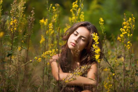 Portrait of a young woman on flowers field blured background