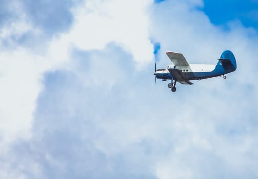 Biplane In Blue Sky Over Clouds