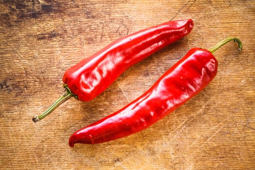 Red hot chili peppers on old wooden table surface texture background