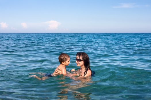 Mom teaches son to swim in the sea